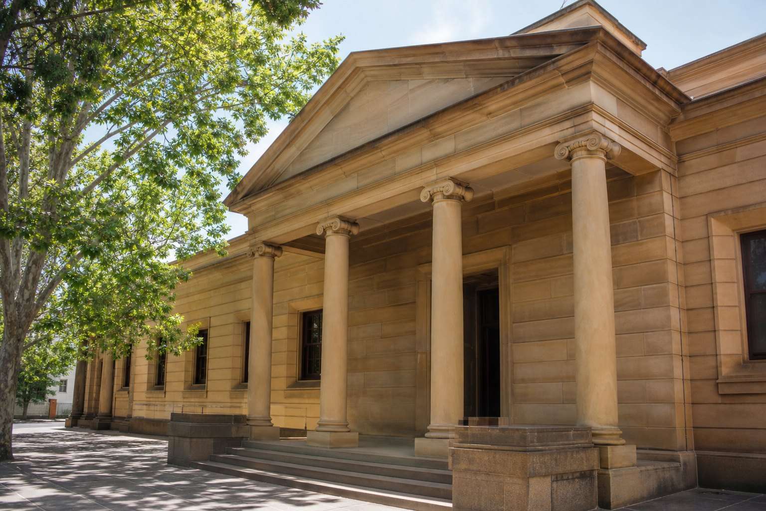 A sandstone courthouse portico under a clear sky